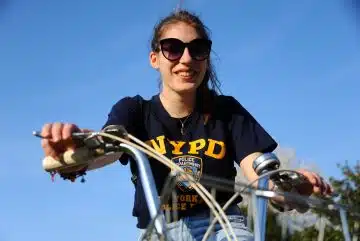 woman in black and yellow crew neck t-shirt riding bicycle during daytime