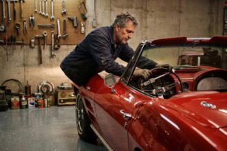 Propriétaire installant un antivol sur le volant d'une voiture de collection ancienne dans un garage privé