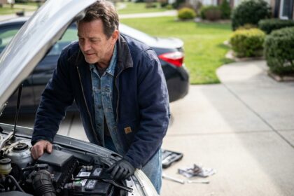 Homme d'âge moyen examine la batterie d'une voiture en extérieur