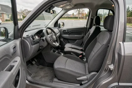 Intérieur d'une voiture sans permis 4 places vue depuis la porte conducteur, avec tableau de bord, volant et banquette arrière